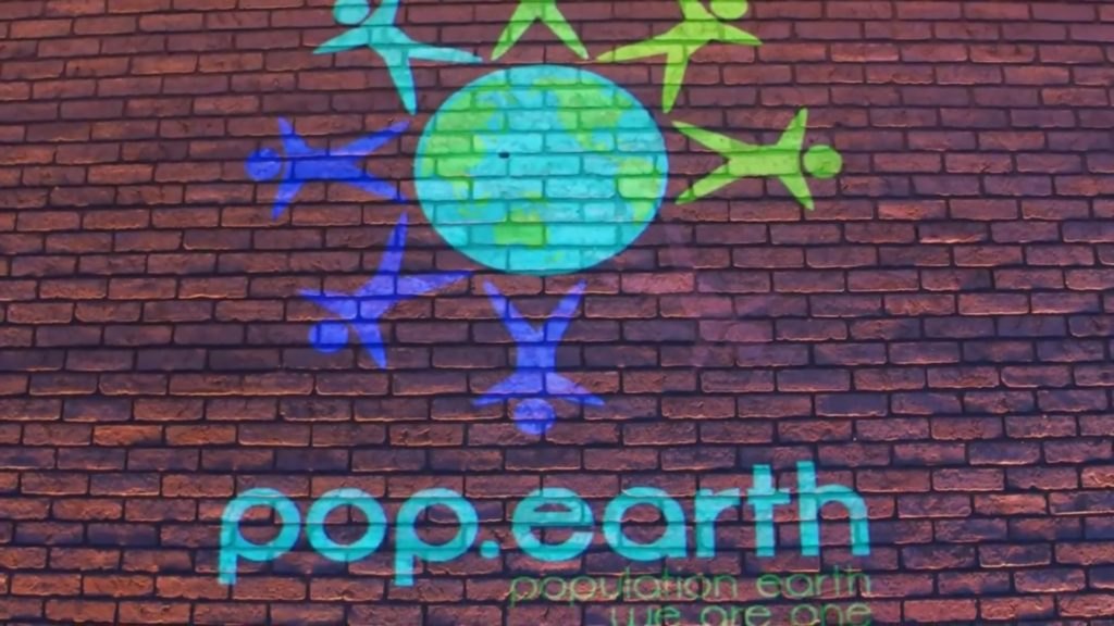 Pop.Earth mural painted on a brick wall showing people circling the earth