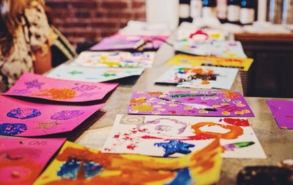 Bright paintings drying on a table at a FREE TO BE ME Art session